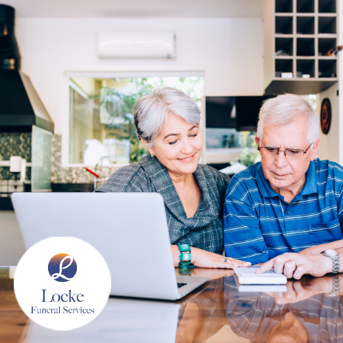 Older man and woman smiling and looking down at calculator and paper